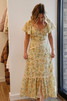 a woman standing in front of a window wearing a dress with ruffles on it