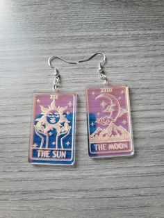 This listing is for one pair of iridescent The Sun and The Moon mismatched acrylic tarot card earrings. The engraved areas shimmer in the light! The iridescent acrylic sometimes has a slight bubbling in spots. I do my best to avoid this and it's usually barely noticeable unless up close! Doesn't take away from the shimmer though! These are about 2 inches and very lightweight. These are laser cut acrylic! Jewelry hardware is hypo allergenic stainless steel. Leverbacks are available upon request! Tarot Card Earrings, Tarot Earrings, Acrylic Earrings Laser Cut, Laser Jewelry, Laser Cut Jewelry Acrylic, Card Earrings, Witchy Earrings, Moon Tarot Card, Laser Engraved Acrylic