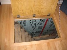 an open wooden box sitting on top of a hard wood floor next to a wall