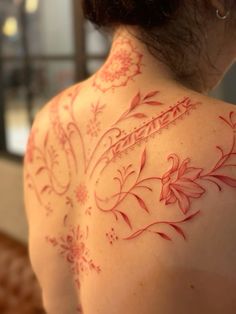 the back of a woman's shoulder with red flowers on it and an intricate design