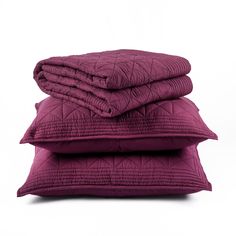 two pillows stacked on top of each other in front of a white background with purple quilting