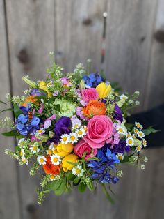 a bouquet of colorful flowers in front of a wooden fence