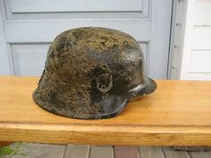 an old helmet sitting on top of a wooden bench