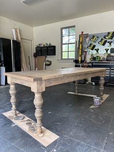 a large wooden table in a garage with tools hanging on the wall and flooring around it