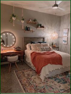 a bed room with a neatly made bed next to a desk and mirror on the wall