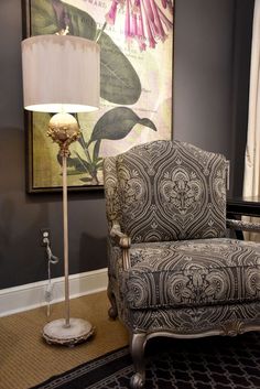 a living room with a chair, lamp and painting on the wall in it's corner