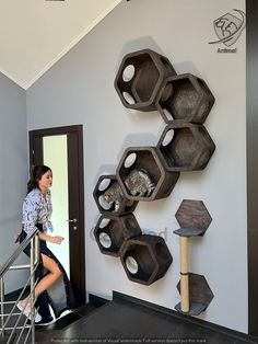 a woman is walking up the stairs in front of a wall with hexagonal shelves