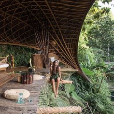 a woman sitting on a hammock next to a body of water and trees