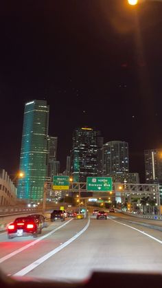 cars driving down the highway at night with skyscrapers in the background