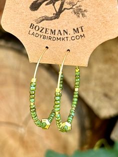 Introducing our vibrant Boho Seed Bead Hoop Earrings! These are the perfect blend of bohemian charm and contemporary style, featuring a delicate gold-colored hoop adorned with hunter-green earth-toned Czech glass seed beads with an eye-catching gold centerpiece. The beads, available in a kaleidoscope of hues, create an eye-catching mosaic.Our Boho Seed Bead Hoop Earrings are also incredibly lightweight, ensuring optimal comfort. Whether you're heading to a music festival, a beach getaway, or simply want to add a pop of color to your everyday ensemble, these earrings are the perfect choice. They effortlessly elevate any outfit, from casual boho-chic looks to more elegant and sophisticated styles. Gold Hoop Earrings With Tiny Beads For Summer, Bohemian Hoop Beaded Earrings With Faceted Beads, Green Beaded Hoop Earrings For Summer, Bohemian Hoop Earrings With Gold Beads Adjustable, Bohemian Beaded Hoop Earrings For Everyday, Bohemian Gold Beaded Hoop Earrings, Summer Beaded Green Hoop Earrings, Summer Green Beaded Hoop Earrings, Everyday Bohemian Beaded Hoop Earrings