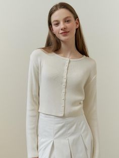 This is a classic cardigan with a simple, chic design. It has a round neckline and a full button placket with small, evenly spaced buttons. The cardigan is designed with a fitted silhouette and long sleeves, suggesting a snug and comfortable fit. A small, discreet logo or emblem is visible on the front, indicating a touch of branding.- Round neckline and full button placket are key features.- Fitted silhouette with long sleeves.- A subtle logo embellishes the front of the cardigan. Elegant Button-up Sweater, Elegant Solid Color Button-up Sweater, Chic Crew Neck Cardigan With Buttons, Everyday Fitted Fine Knit Cardigan, Elegant Crew Neck Cardigan For Layering, Classic Fine Knit Spring Cardigan, Elegant Everyday Cardigan With Buttons, Classic Long Sleeve Cardigan For Everyday, Classic Long Sleeve Everyday Cardigan