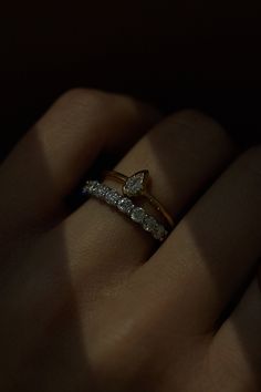 a woman's hand with a diamond ring on top of her finger in the dark