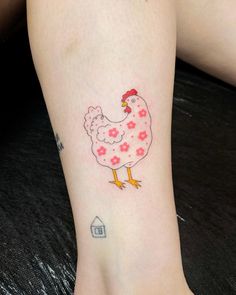 a chicken tattoo on the foot of a woman's leg, with pink flowers around it