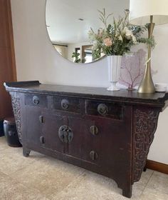 an antique dresser with mirror and vase on top