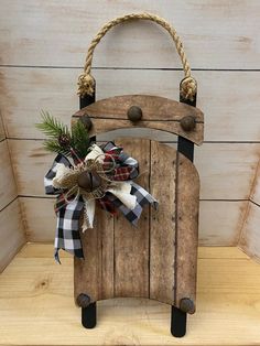 an old wooden sled with a bow and pine cone on the handle is sitting on a shelf