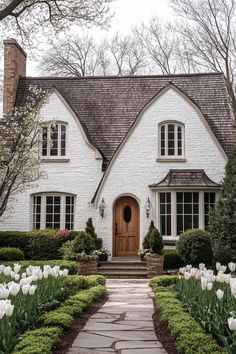 a white brick house with tulips in the front yard and walkway leading up to it