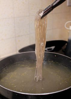 a person is stirring something in a pan on the stove top with a large spatula