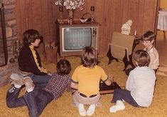 five children sitting on the floor in front of an old tv playing video games together