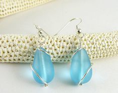 a pair of blue earrings sitting on top of a white piece of cloth