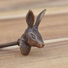 a small metal rabbit head on top of a wooden table next to a screwdriver