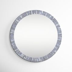 a round mirror with blue and white stripes on it's edge, hanging from the wall