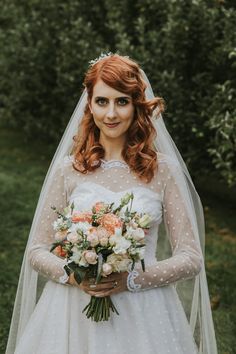 a woman in a white wedding dress holding a bouquet of flowers and wearing makeup on her face