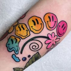 a tattoo with smiley faces and flowers on it