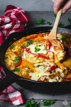 a skillet filled with chicken and cheese covered in sauce