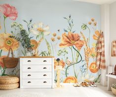 a white dresser sitting next to a wall with flowers painted on the walls and drawers