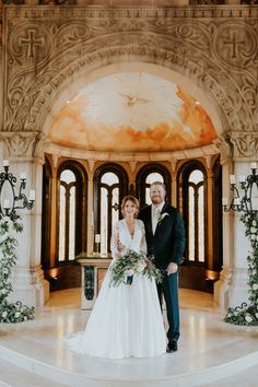 a bride and groom posing for a photo in front of an ornate archway