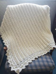 a white crocheted blanket sitting on top of a chair