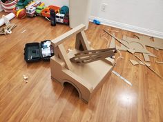 a cardboard car sitting on top of a hard wood floor next to construction supplies and tools