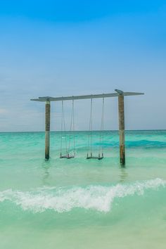 two wooden swings in the ocean with waves