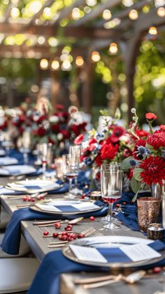 a long table is set with blue and red place settings, silverware, and wine glasses