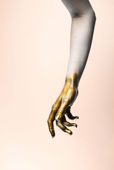 a person's hand with gold painted on it and white paint all over their body