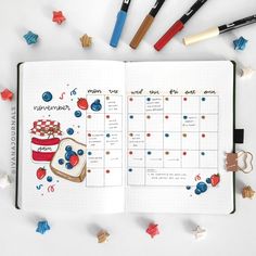 an open planner with food on it next to markers and pencils in the shape of stars