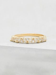 a yellow gold ring with five diamonds on it, sitting on top of a white surface