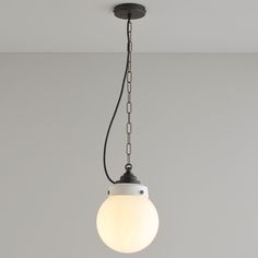 a light fixture hanging from the ceiling in a room with white walls and grey flooring