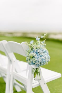 a bouquet of blue flowers sitting on top of a white bench next to a green field