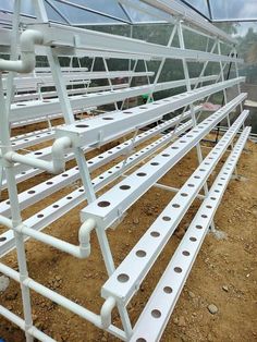 the inside of a baseball dugout with white plastic pipes and seats in dirt area