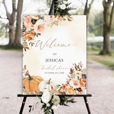 a welcome sign with white flowers and greenery is displayed on an easel outside