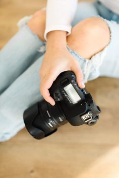 a woman sitting on the floor holding a camera