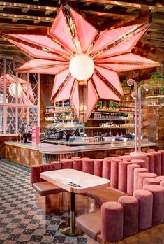 the interior of a restaurant with pink booths and tables in front of a large star hanging from the ceiling