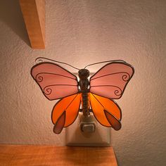 a light that is on top of a wooden table with a butterfly lamp in front of it