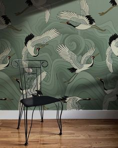 a chair sitting in front of a wallpaper with cranes on it's back