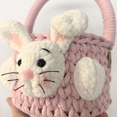 a crocheted pink and white purse with a bunny face on the front, in someone's hand