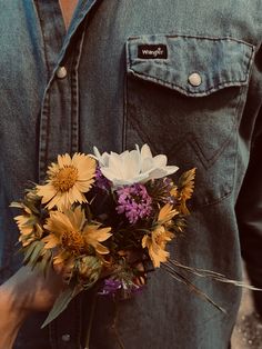 a man holding a bouquet of flowers in his hand and wearing a denim shirt on the other side