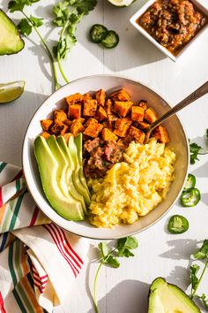 a bowl filled with mashed potatoes, avocado and other food on a table