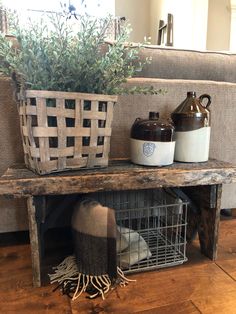 a wooden table topped with a basket filled with green plants next to a gray couch