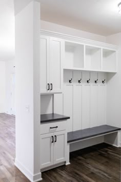 an empty room with white cabinets and black counter tops in the center is a wood floor